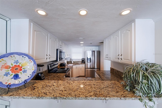 1051 Ocean Shore Blvd Unit 502, Ormond Beach, FL 32176 - kitchen featuring appliances with stainless steel finishes, recessed lighting, a peninsula, light stone countertops, and white cabinetry