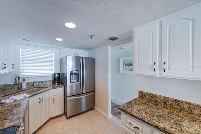 1051 Ocean Shore Blvd Unit 502, Ormond Beach, FL 32176 - kitchen with stainless steel fridge, white cabinets, dark stone countertops, light tile patterned floors, and recessed lighting