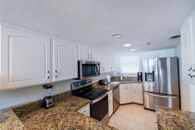1051 Ocean Shore Blvd Unit 502, Ormond Beach, FL 32176 - kitchen featuring appliances with stainless steel finishes, white cabinetry, dark stone counters, recessed lighting, and a textured ceiling