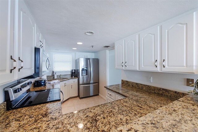 1051 Ocean Shore Blvd Unit 502, Ormond Beach, FL 32176 - kitchen featuring appliances with stainless steel finishes, dark stone countertops, white cabinets, light tile patterned flooring, and recessed lighting