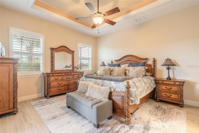 2939 Bella Flore Ter, New Smyrna Beach, FL 32168 - bedroom featuring multiple windows, a tray ceiling, light wood-style floors, and a ceiling fan