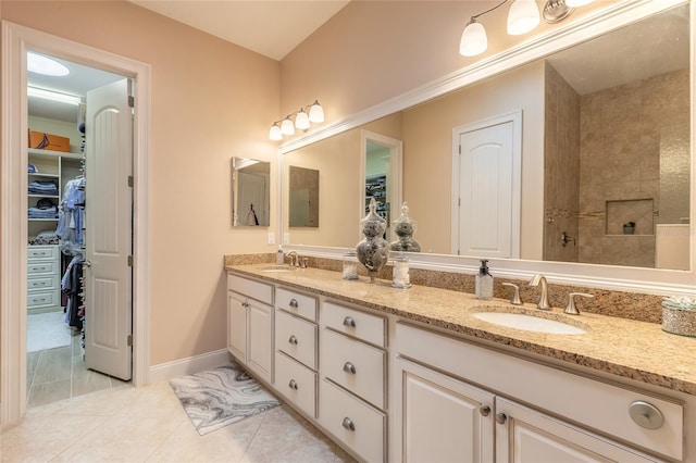 2939 Bella Flore Ter, New Smyrna Beach, FL 32168 - bathroom featuring double vanity, tile patterned flooring, a spacious closet, and tiled shower