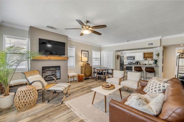 402 N Orange St, New Smyrna Beach, FL 32168 - living area with light wood-style flooring, a ceiling fan, a large fireplace, healthy amount of natural light, and ornamental molding