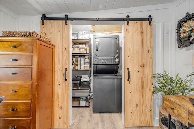 402 N Orange St, New Smyrna Beach, FL 32168 - laundry room featuring a barn door, stacked washer / dryer, light wood-type flooring, and wood ceiling