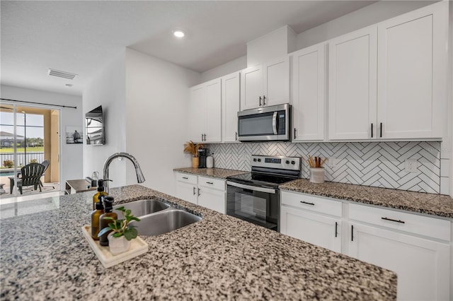 3116 Crab Trap Dr, New Smyrna Beach, FL 32168 - kitchen featuring appliances with stainless steel finishes, tasteful backsplash, light stone countertops, white cabinets, and recessed lighting