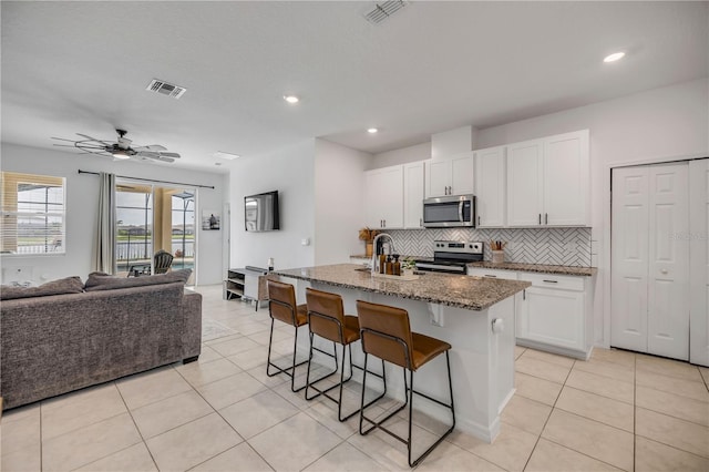 3116 Crab Trap Dr, New Smyrna Beach, FL 32168 - kitchen with appliances with stainless steel finishes, open floor plan, a kitchen bar, light tile patterned floors, and recessed lighting