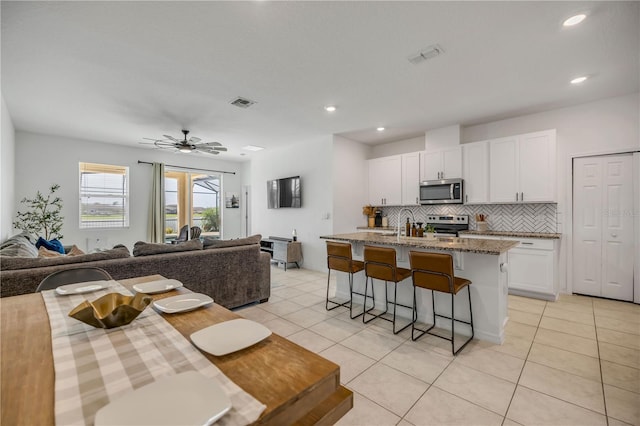 3116 Crab Trap Dr, New Smyrna Beach, FL 32168 - kitchen with stainless steel appliances, open floor plan, a breakfast bar area, white cabinets, and backsplash