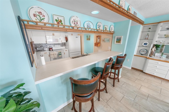 2967 S Atlantic Ave Unit 508, Daytona Beach, FL 32118 - kitchen featuring white appliances, white cabinets, a breakfast bar area, a peninsula, and built in study area