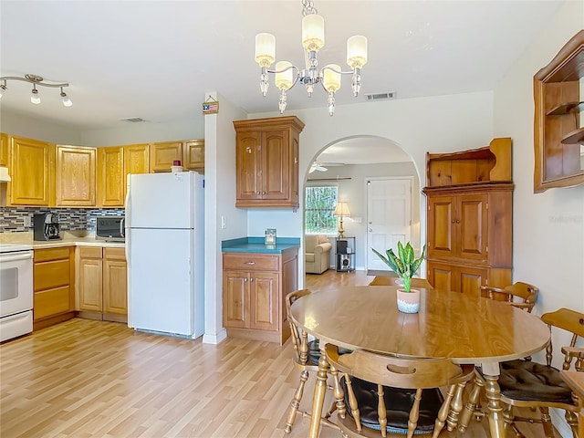 1331 Needle Palm Dr, Edgewater, FL 32132 - kitchen featuring white appliances, arched walkways, a chandelier, light wood-style floors, and backsplash