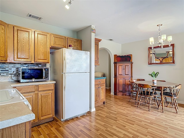 1331 Needle Palm Dr, Edgewater, FL 32132 - kitchen with freestanding refrigerator, stainless steel microwave, arched walkways, light wood finished floors, and backsplash