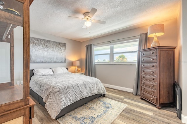 325 N Causeway Unit B305, New Smyrna Beach, FL 32169 - bedroom with a textured ceiling, light wood finished floors, and a ceiling fan