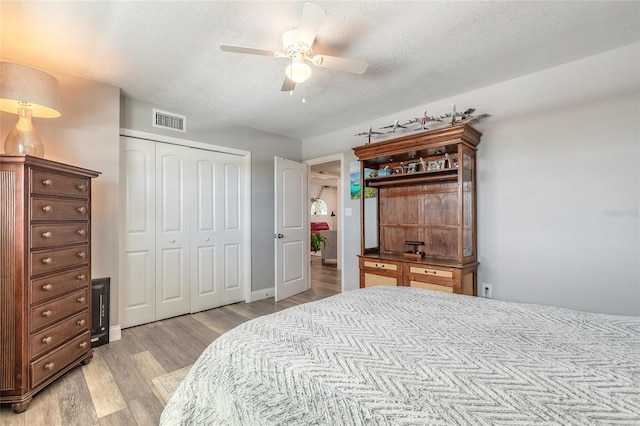 325 N Causeway Unit B305, New Smyrna Beach, FL 32169 - bedroom with light wood-type flooring, a closet, a textured ceiling, and a ceiling fan