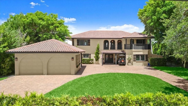 206 Canova Dr, New Smyrna Beach, FL 32169 - mediterranean / spanish-style home featuring stucco siding, a balcony, a front lawn, a tile roof, and a detached garage