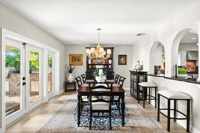 206 Canova Dr, New Smyrna Beach, FL 32169 - dining space with a chandelier, light wood finished floors, arched walkways, and french doors