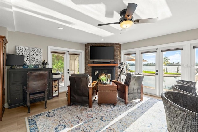 206 Canova Dr, New Smyrna Beach, FL 32169 - living room with french doors, a large fireplace, light wood-style floors, a ceiling fan, and recessed lighting
