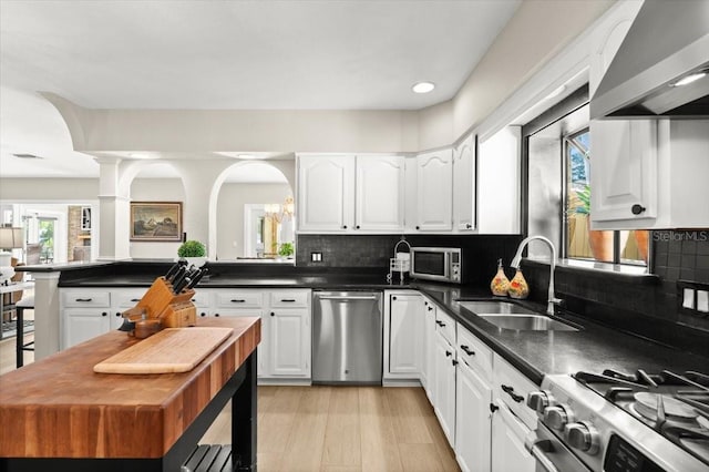 206 Canova Dr, New Smyrna Beach, FL 32169 - kitchen featuring stainless steel appliances, extractor fan, white cabinets, dark countertops, and recessed lighting