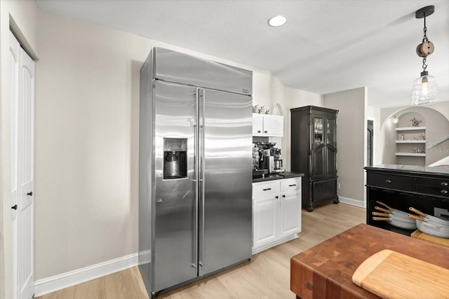 206 Canova Dr, New Smyrna Beach, FL 32169 - kitchen with built in refrigerator, light wood-style flooring, dark countertops, and decorative light fixtures