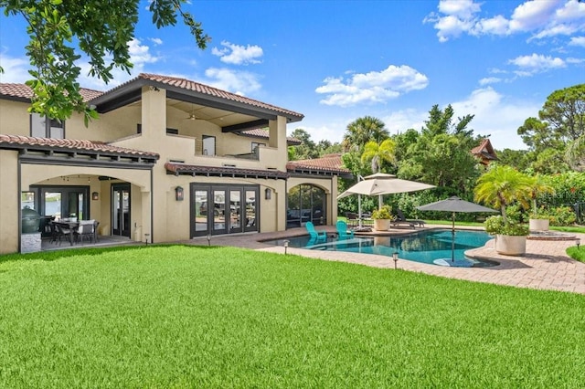 206 Canova Dr, New Smyrna Beach, FL 32169 - rear view of property featuring french doors, a lawn, stucco siding, and an outdoor pool