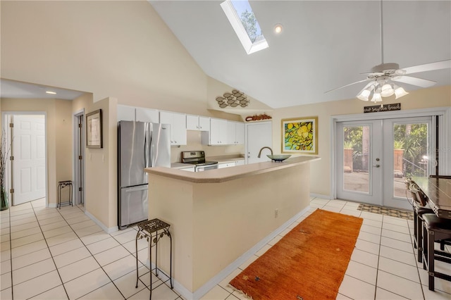 527 Old Minorcan Trl, New Smyrna Beach, FL 32168 - kitchen with range with electric stovetop, freestanding refrigerator, light tile patterned floors, high vaulted ceiling, and white cabinets