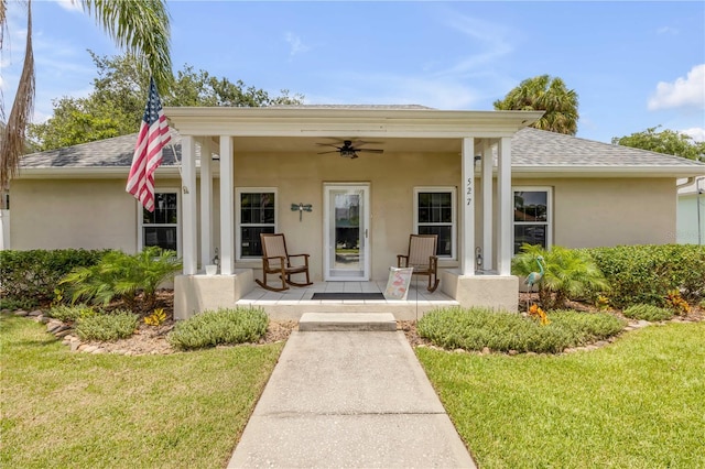 527 Old Minorcan Trl, New Smyrna Beach, FL 32168 - view of exterior entry featuring stucco siding, a ceiling fan, a lawn, and a shingled roof