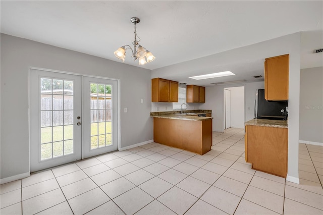 3132 Pine Tree Dr, Edgewater, FL 32141 - kitchen with refrigerator, a peninsula, brown cabinetry, a chandelier, and french doors
