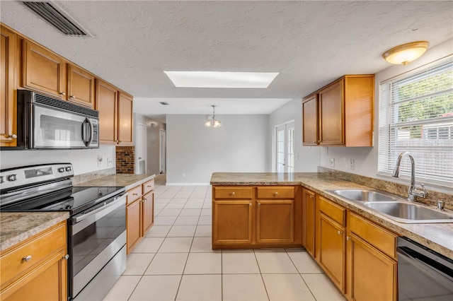 3132 Pine Tree Dr, Edgewater, FL 32141 - kitchen featuring appliances with stainless steel finishes, a skylight, light tile patterned floors, a chandelier, and brown cabinetry