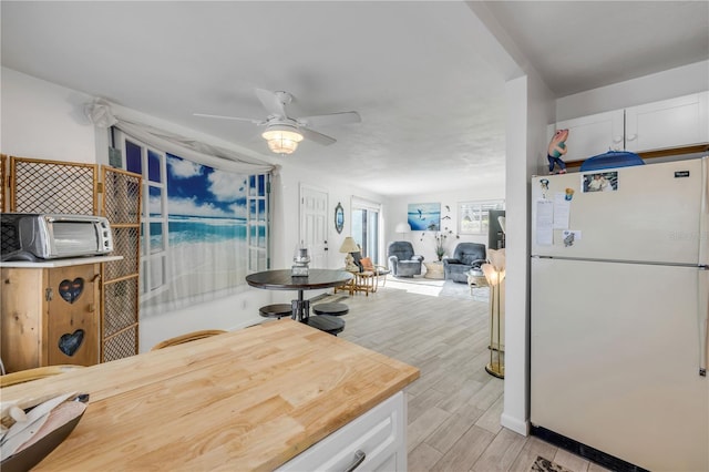1404 N Atlantic Ave Unit 70, Daytona Beach, FL 32118 - kitchen featuring freestanding refrigerator, white cabinetry, light wood finished floors, ceiling fan, and open floor plan