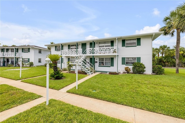 1750 S Palmetto Ave Unit 24, Daytona Beach, FL 32119 - view of front facade with a front yard, stairs, a porch, and stucco siding
