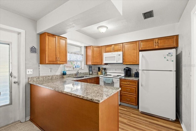 211 Fox Pl, Port Orange, FL 32127 - kitchen with white appliances, brown cabinetry, a peninsula, light stone countertops, and tasteful backsplash