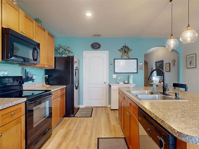 2731 Star Coral Ln, New Smyrna Beach, FL 32168 - kitchen with black appliances, arched walkways, light wood-type flooring, light countertops, and decorative light fixtures