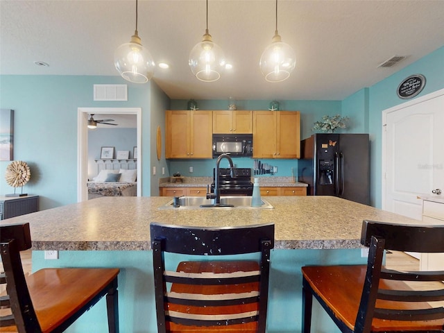2731 Star Coral Ln, New Smyrna Beach, FL 32168 - kitchen with black appliances, a breakfast bar area, and hanging light fixtures