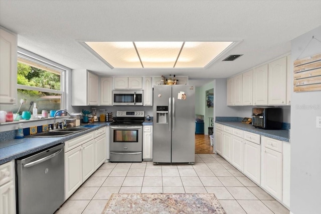 20 Putnam Ave, Ormond Beach, FL 32174 - kitchen with stainless steel appliances, light tile patterned floors, white cabinetry, and dark countertops