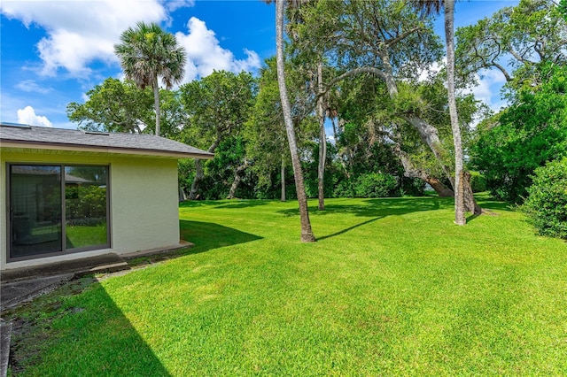 view of green lawn featuring view of wooded area