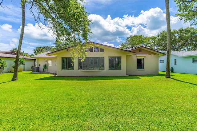 back of property with stucco siding and a yard