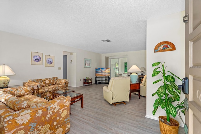 living area with a textured ceiling and light wood finished floors