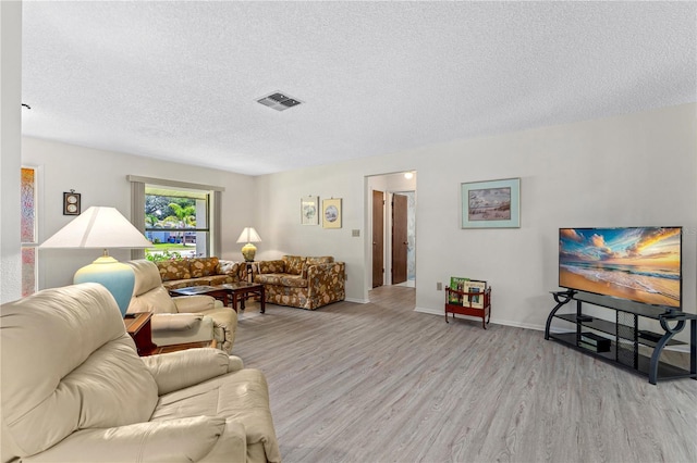 living area featuring light wood-type flooring and a textured ceiling