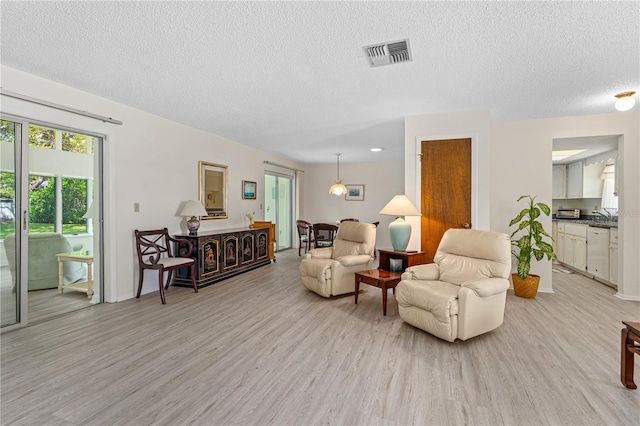 living area featuring light wood-style floors, a textured ceiling, and healthy amount of natural light