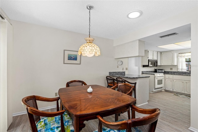 dining room with light wood-style flooring and a textured ceiling