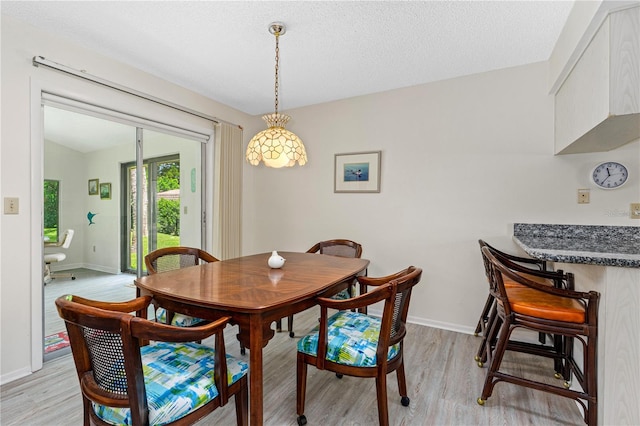 dining space featuring light wood-style flooring and a textured ceiling