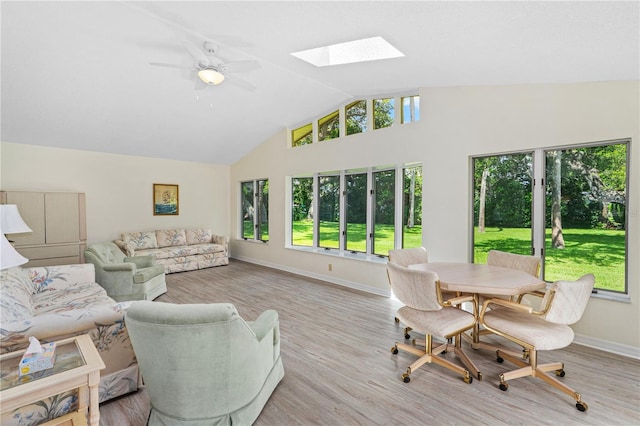living area featuring healthy amount of natural light, a skylight, wood finished floors, and high vaulted ceiling