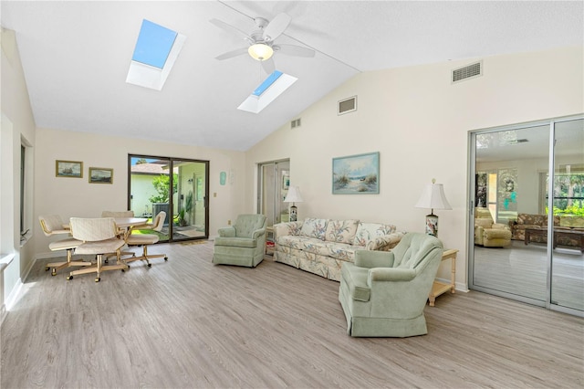 living area featuring wood finished floors, healthy amount of natural light, a skylight, ceiling fan, and high vaulted ceiling