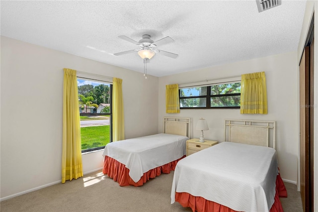 carpeted bedroom featuring multiple windows, a ceiling fan, a closet, and a textured ceiling