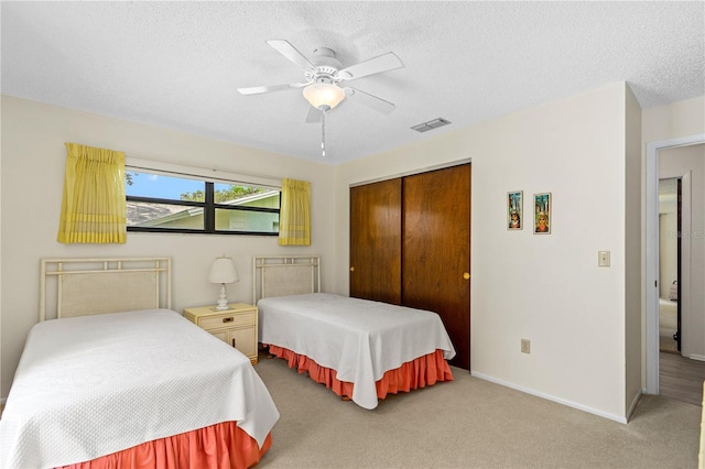 carpeted bedroom with a closet, a textured ceiling, and ceiling fan