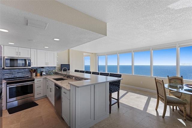 2625 S Atlantic Ave Unit 28Se, Daytona Beach Shores, FL 32118 - kitchen with appliances with stainless steel finishes, a peninsula, a kitchen bar, a textured ceiling, and tasteful backsplash