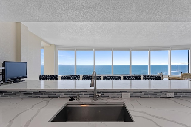 2625 S Atlantic Ave Unit 28Se, Daytona Beach Shores, FL 32118 - kitchen featuring a water view, a textured ceiling, light stone counters, and healthy amount of natural light