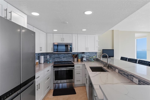 2625 S Atlantic Ave Unit 28Se, Daytona Beach Shores, FL 32118 - kitchen featuring appliances with stainless steel finishes, a textured ceiling, decorative backsplash, light stone countertops, and white cabinetry