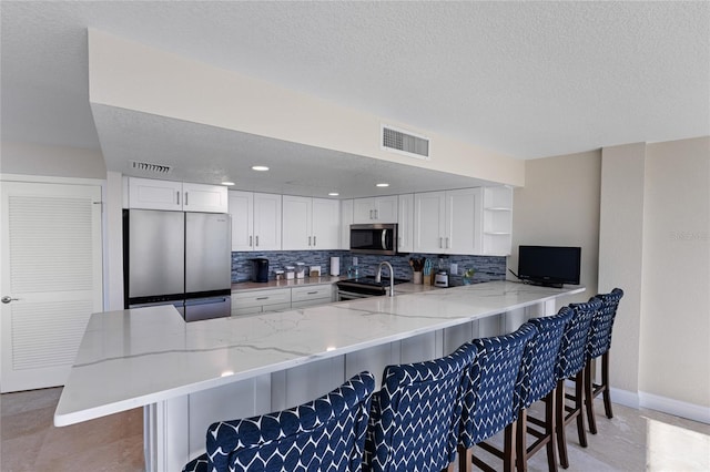 2625 S Atlantic Ave Unit 28Se, Daytona Beach Shores, FL 32118 - kitchen featuring stainless steel appliances, open shelves, a peninsula, white cabinetry, and backsplash