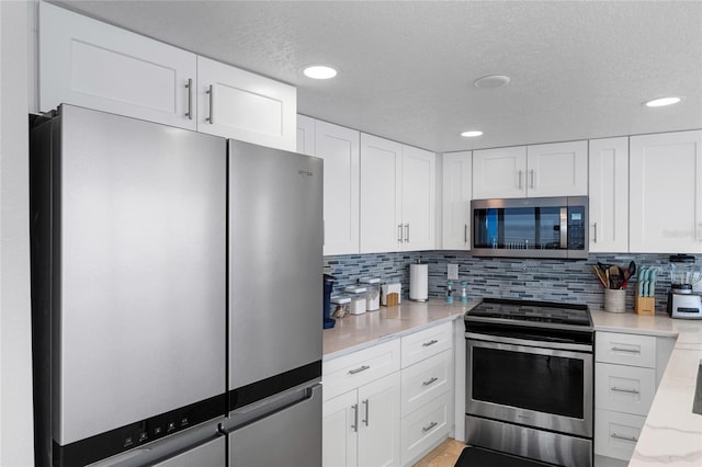 2625 S Atlantic Ave Unit 28Se, Daytona Beach Shores, FL 32118 - kitchen with stainless steel appliances, decorative backsplash, white cabinetry, a textured ceiling, and light stone countertops