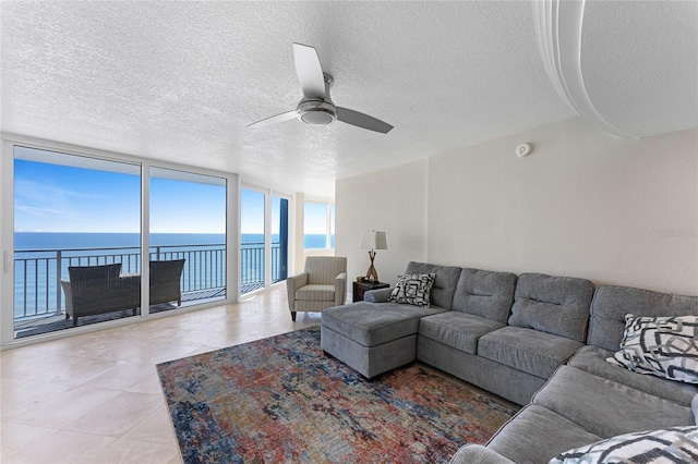 2625 S Atlantic Ave Unit 28Se, Daytona Beach Shores, FL 32118 - tiled living area featuring ceiling fan, a water view, a wall of windows, and a textured ceiling