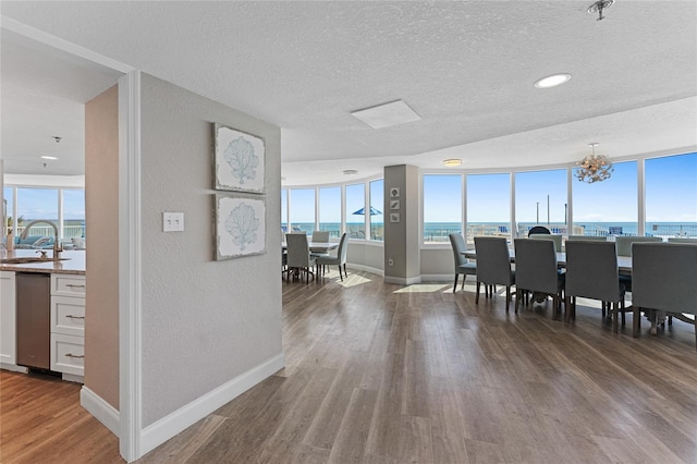 2625 S Atlantic Ave Unit 28Se, Daytona Beach Shores, FL 32118 - dining room with a textured ceiling, wood finished floors, healthy amount of natural light, a chandelier, and a water view